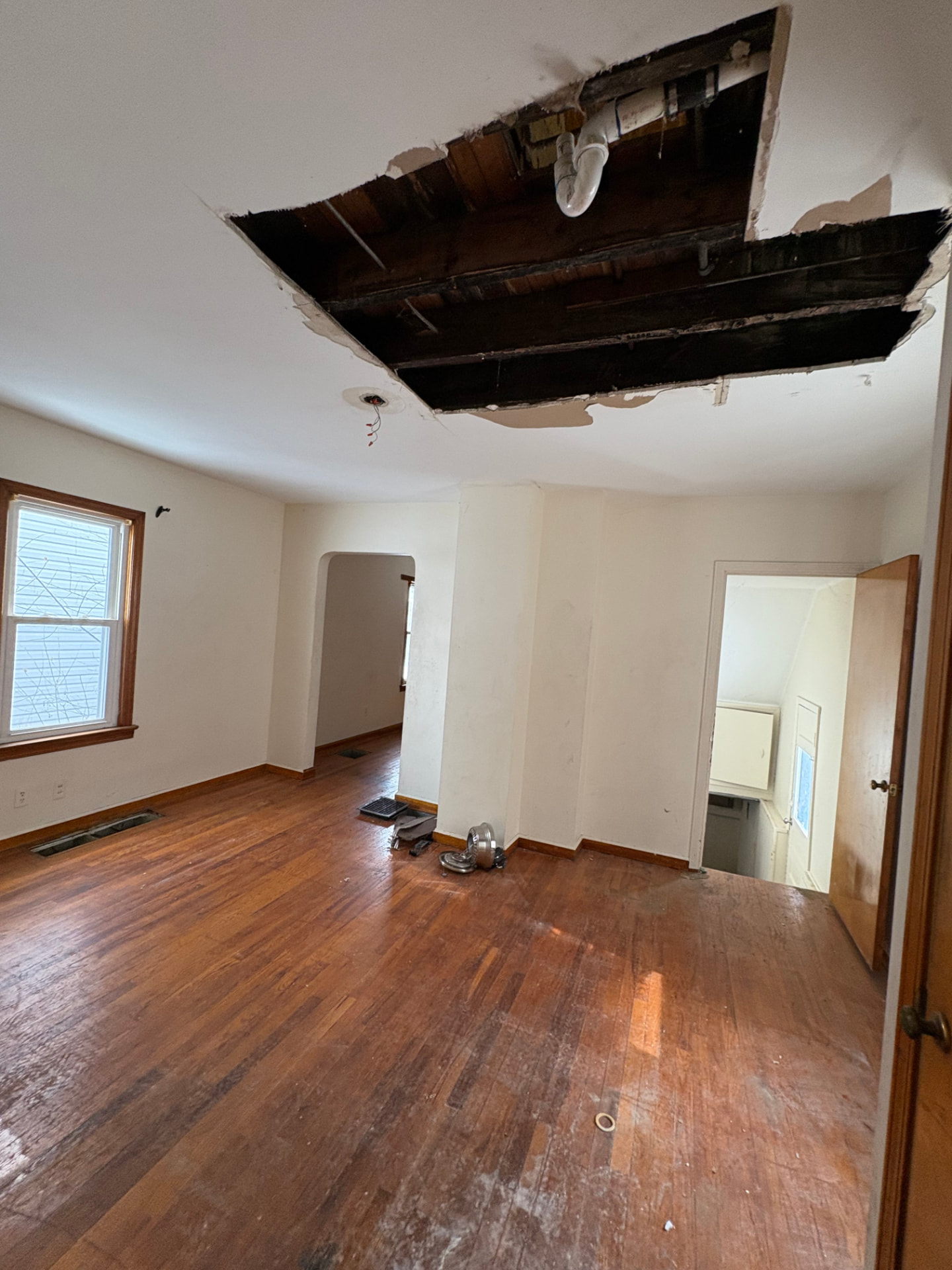 Living room with large section of damaged ceiling drywall removed and exposed joists before repair