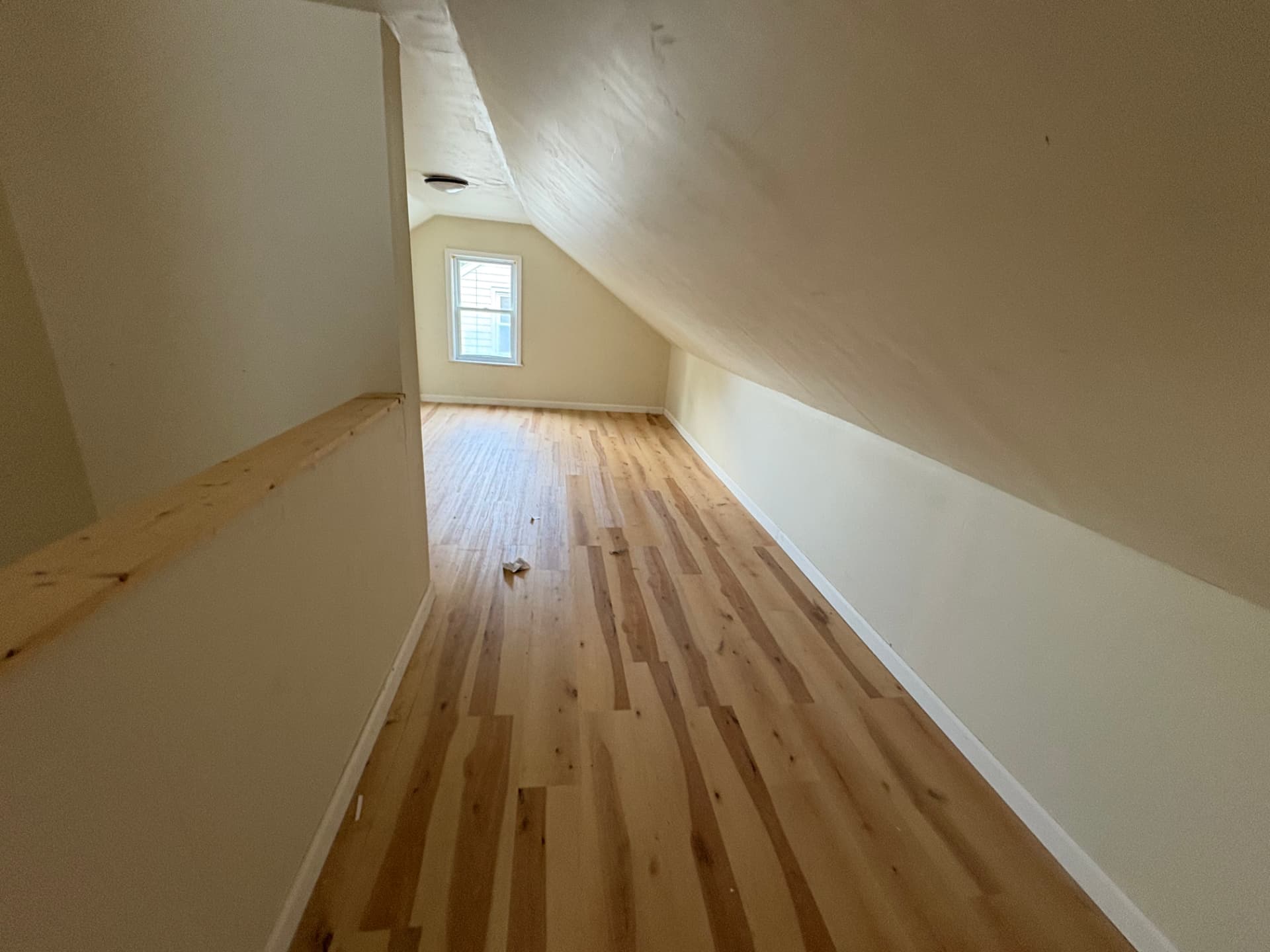 Upstairs loft with sloped ceilings, unfinished wood flooring and construction dust before paint and cleanup
