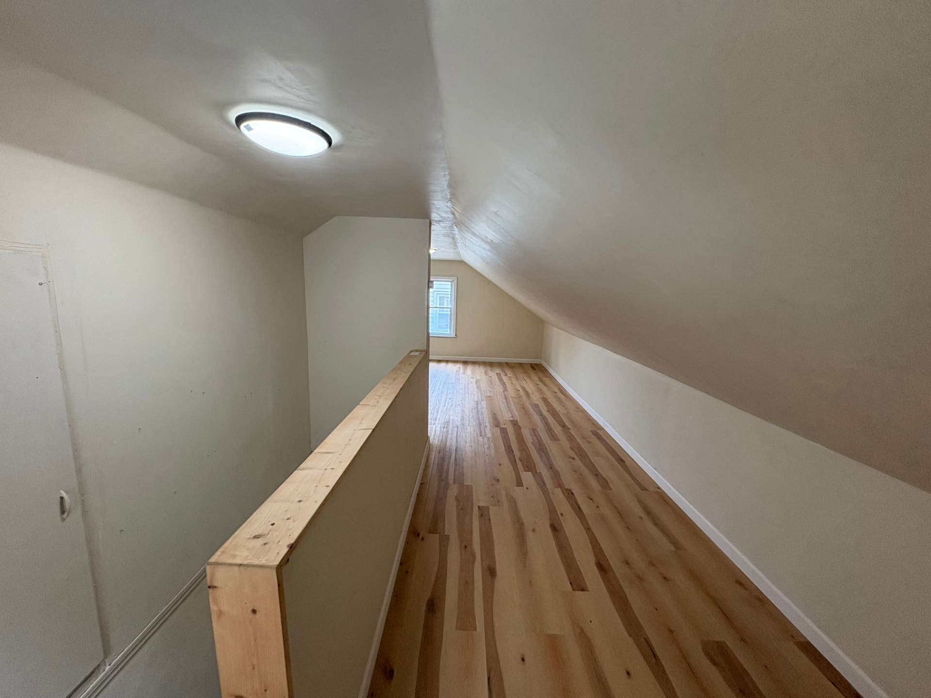 Upstairs loft brightened with fresh paint, cleaned wood flooring and tidy finished space after paint and cleanup